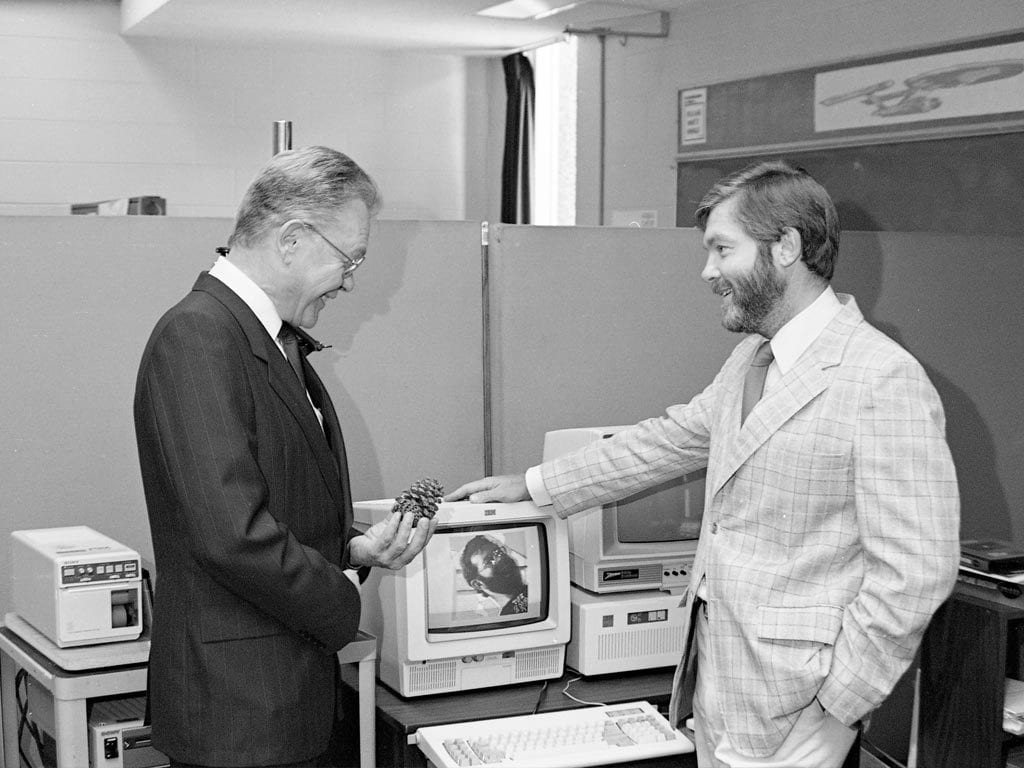 Two researchers beside old computer