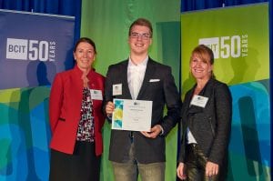 2015 Presentation Idol Winner, Jamie Haakons, standing between the two presenters holding his certificate.