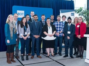 2017 presentation idol finalists standing on a stage in front of a blue background with the BCIT logo on it. The diverse group of students are, from left to right: Julie Cantes, Kevin Hong, Stacey Neves, Dean Tamboline, Matt Leemet, Navtej Heir, Steve Cohos, and Alex Baumann