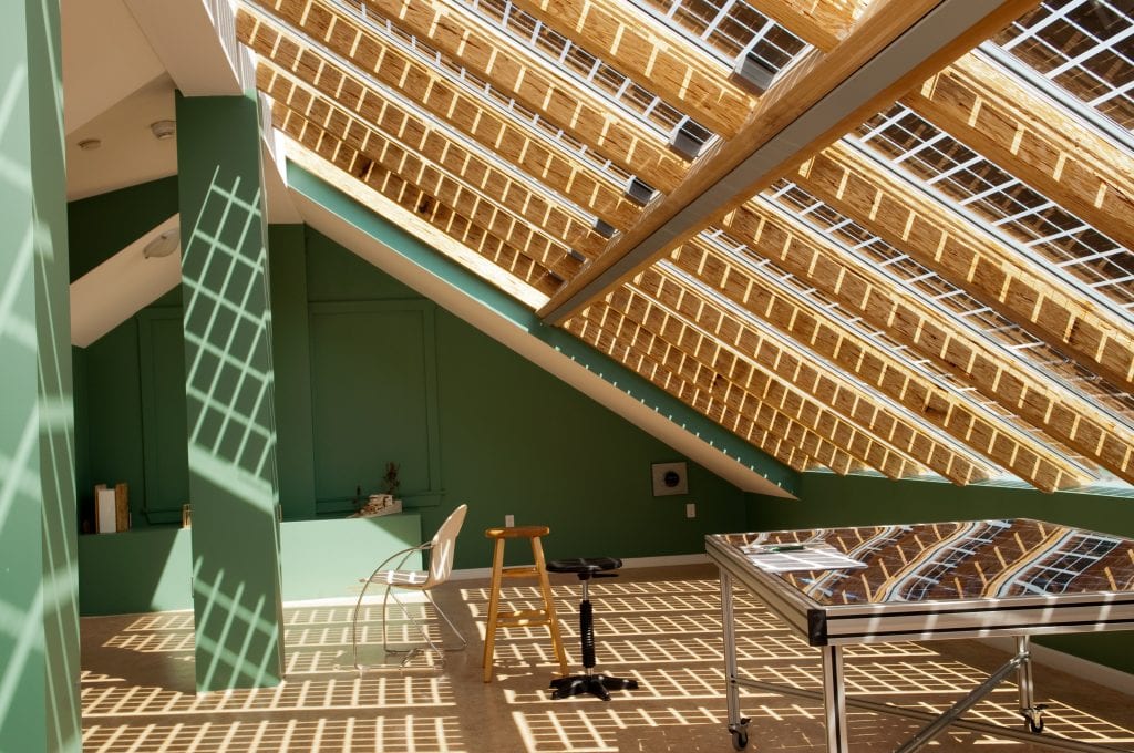 Attic room with a latticed windowed roof casting a shadow on the floor.