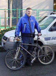 Security man wearing blue uniform holding a mountain bike.