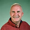 Brian Hosier headshot smiling with rust-red shirt and short hair.