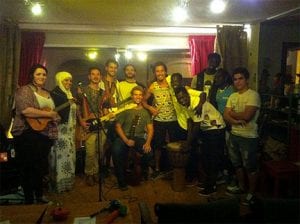 Group of twelve musicians on stage, smiling at the camera after a musical show.