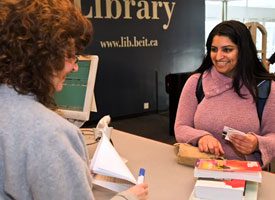 Person checking out books at the library.