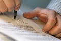 Thumbnail image of person writing on a piece of paper.