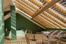attic open design skylight panels casting grid like shadows on room with green walls.