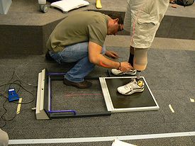 Person squatting and measuring a foot in the motion capture lab.
