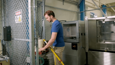 Medium image of person wearing a blue shirt and tan pants in the medium voltage testing lab at bcit.