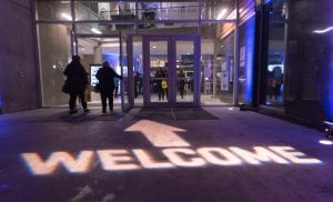 The word welcome and an arrow lighting the ground, pointing to the entrance of a BCIT building.