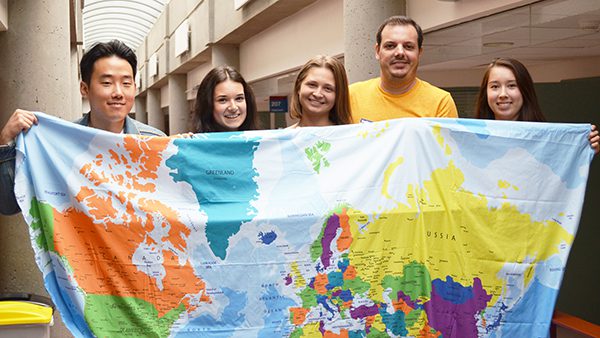 5 people holding a cloth world map.