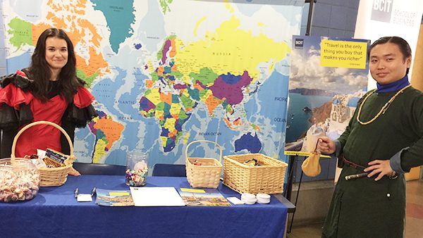 two people at a display booth with a world map behind them.