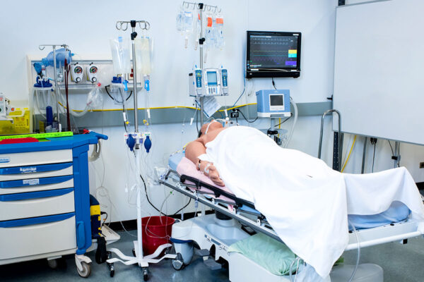 BCIT BSN Nursing hospital room with patient laying in bed under white sheets