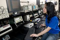 female with black hair and blue t-shirt looking at a computer-like device