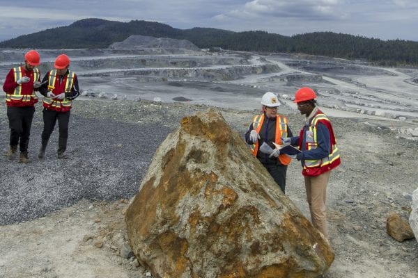 people with safety vests behind big rocks