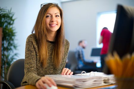 Young woman smiling with a folder open and holdng a mouse