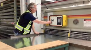 man in hi vis vest and safety glasses using a machine for sheet metal