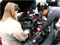 a woman and man look at a car engine