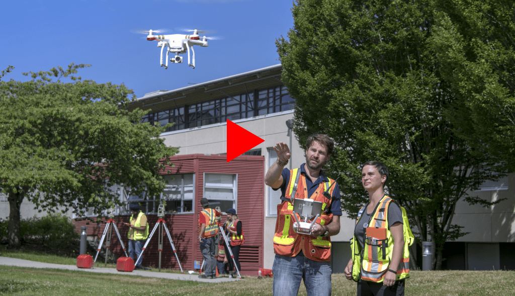 Instructor and student in safety vests watching drone