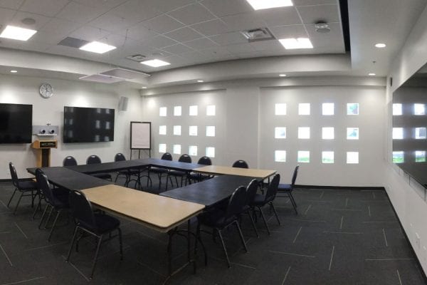 Townhall Square C conference room set up with seating for 14 and 3 wall-mounted TVs.