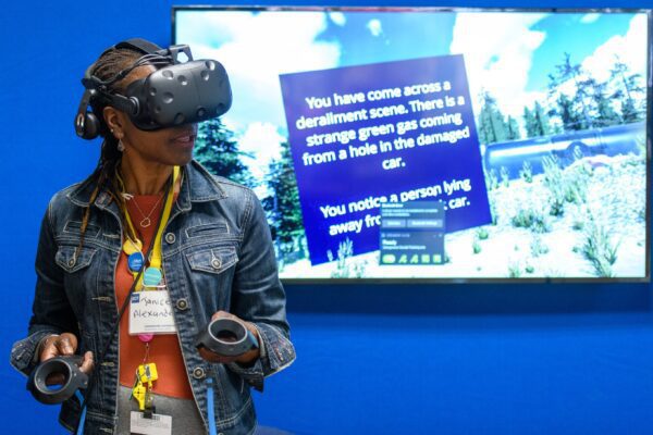 A woman in VR goggles with railway VR screen behind her