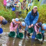 Mark Angelo in a creek looking for salmon with four kids knee deep in water