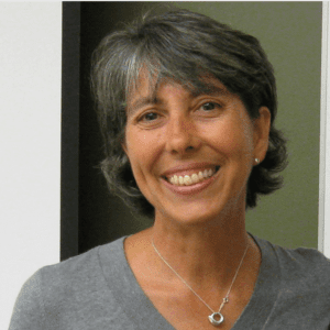 Headshot of Rosario, a female with short brown hair, a grey v-neck sweater and silver necklace