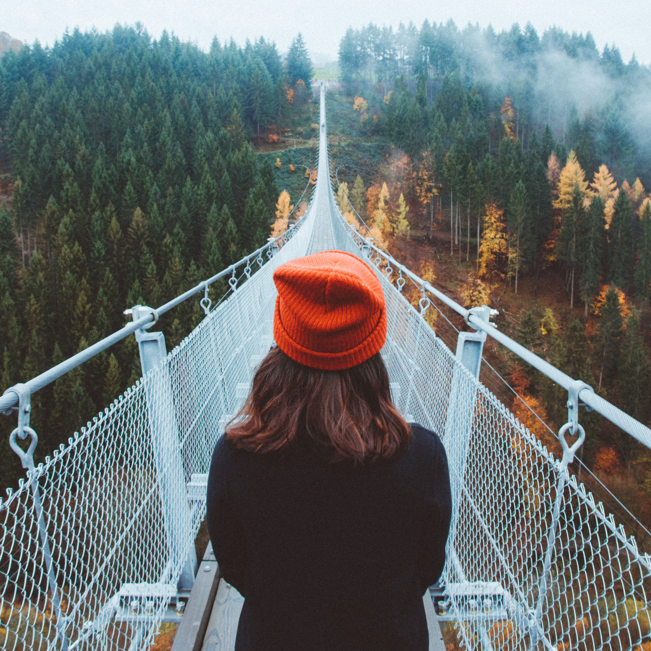 Person standing at entrance to suspension bridge.