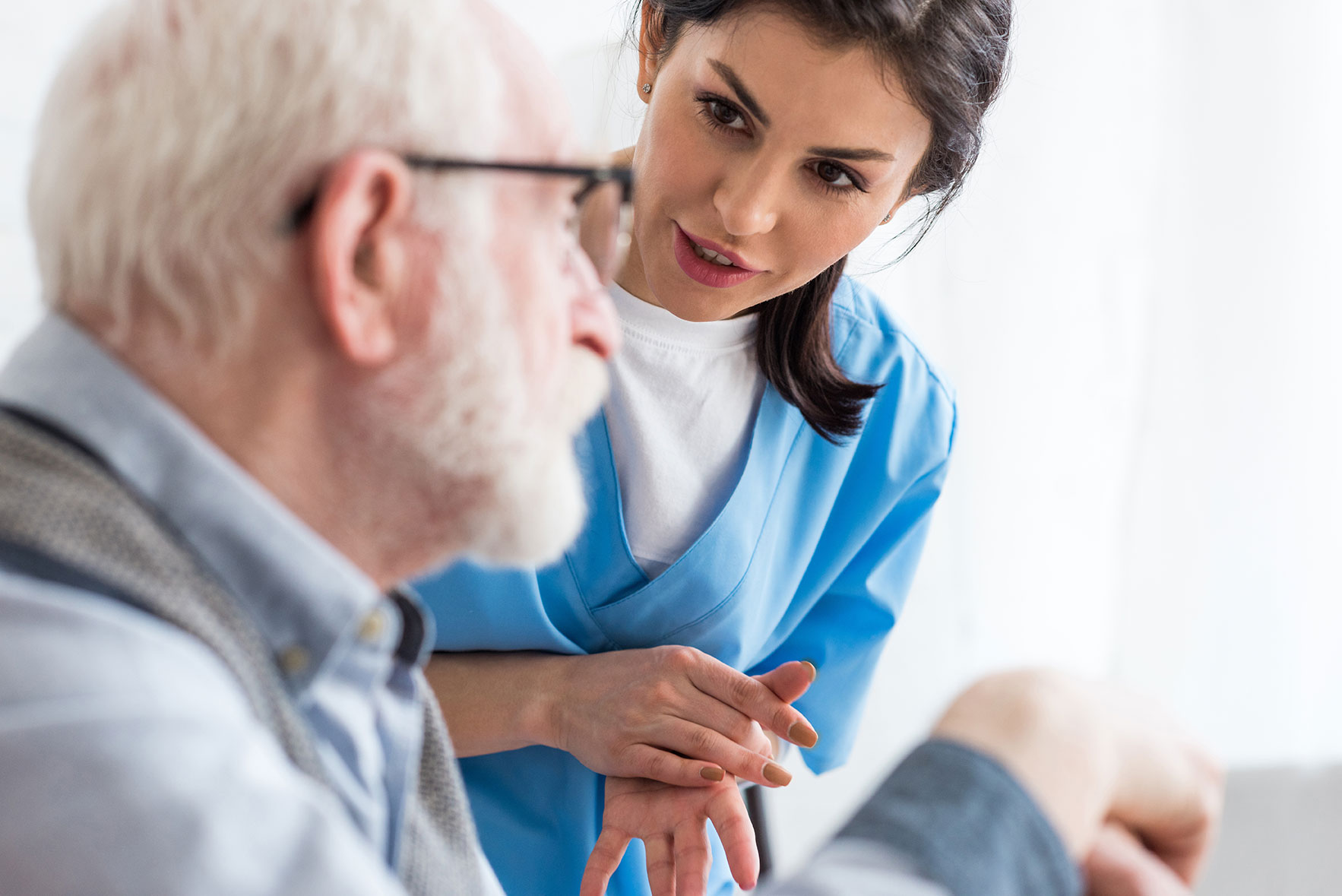 Selective focus of calm nurse talking to elderly patient