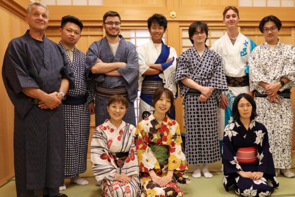 Group photo of students wearing yukata, standing together in a traditional wooden room