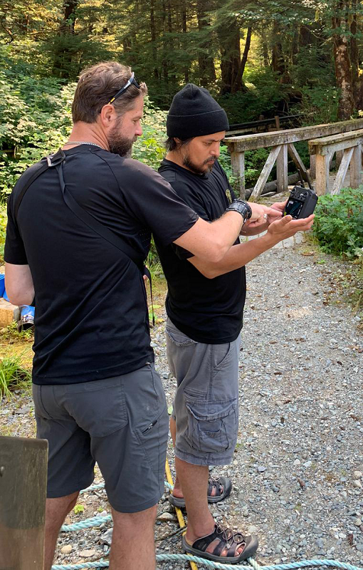 young man holding drone controller while an older man points to the screen