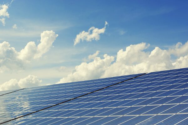 Row of solar panels with blue sky and clouds in the background